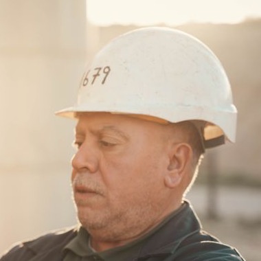 Avi, a project manager in a white hard hat on site